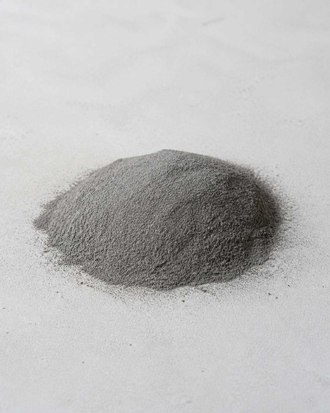 A fine gray mound of high-performance fly ash photographed on a pale mineral surface.