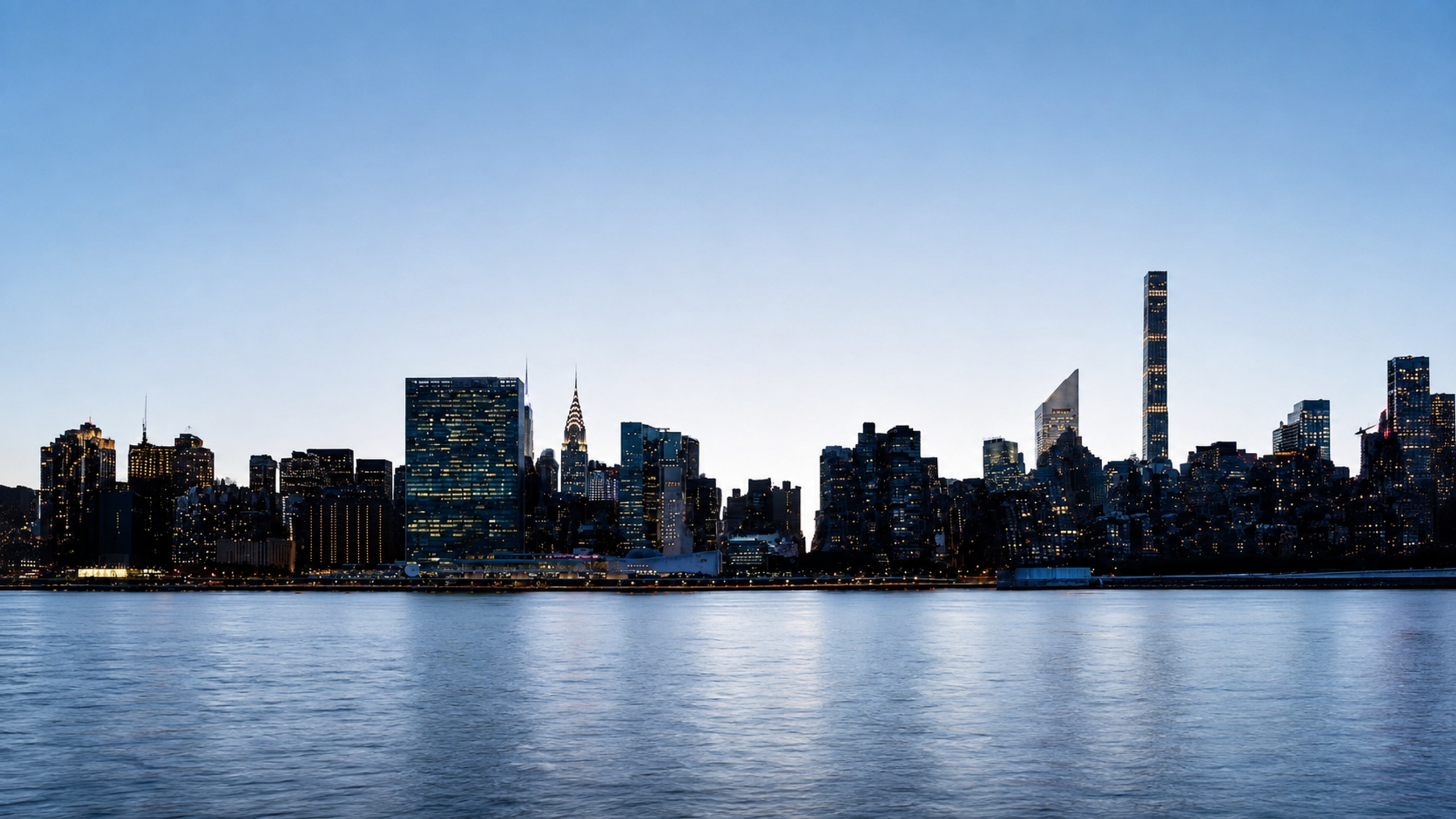 Blue-hour Manhattan skyline panorama with city lights beside the river